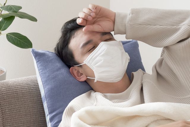 熱で寝込むマスク姿の男性