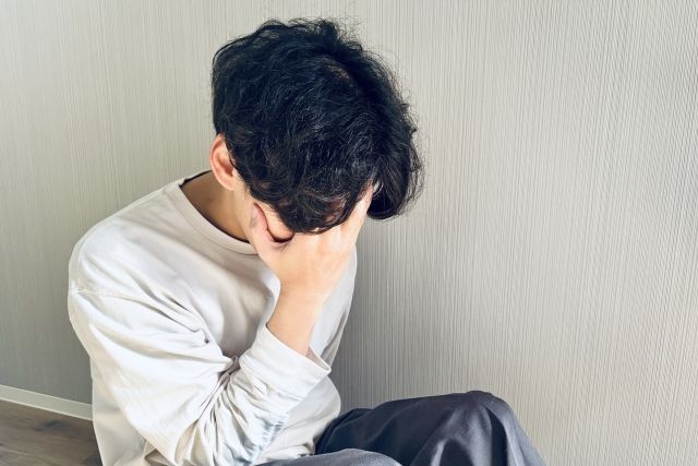 頭を抱えて悩む若い男性
